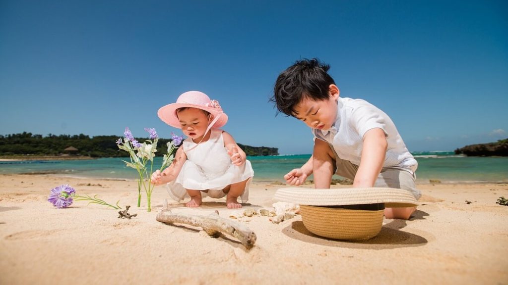 Viajar com bebê: crianças sentadas na praia