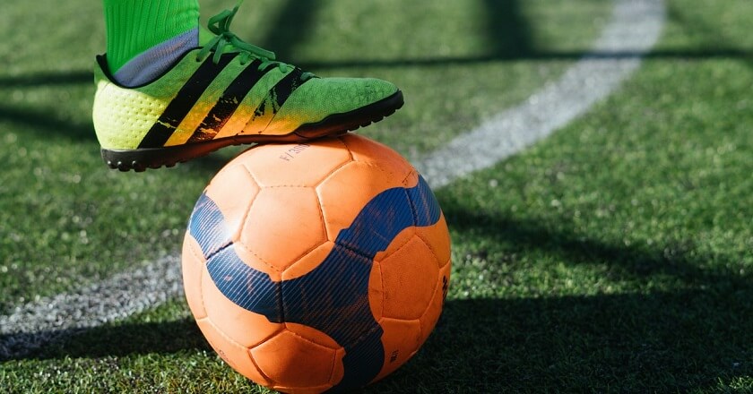 Pé em cima da bola de futebol de campo