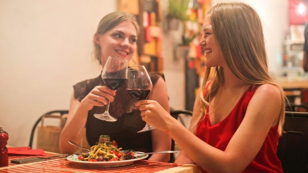 Duas mulheres brindando o Dia dos Namorados com taças de vinho em um jantar romântico
