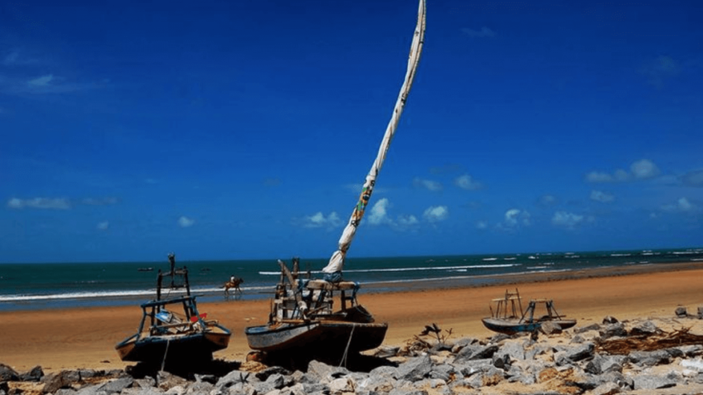 praia de Trairi, com 2 barcos na areia próximos de pedras