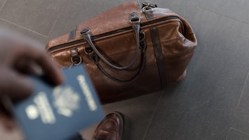 Uma pessoa segurando um passaporte e uma mala.