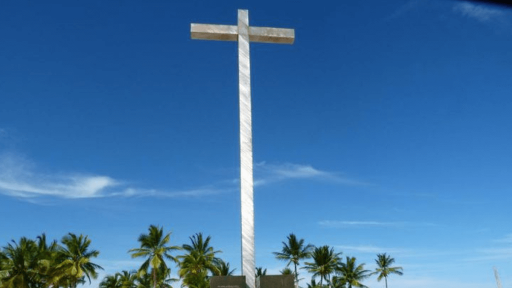 Grande cruz branca em praia.