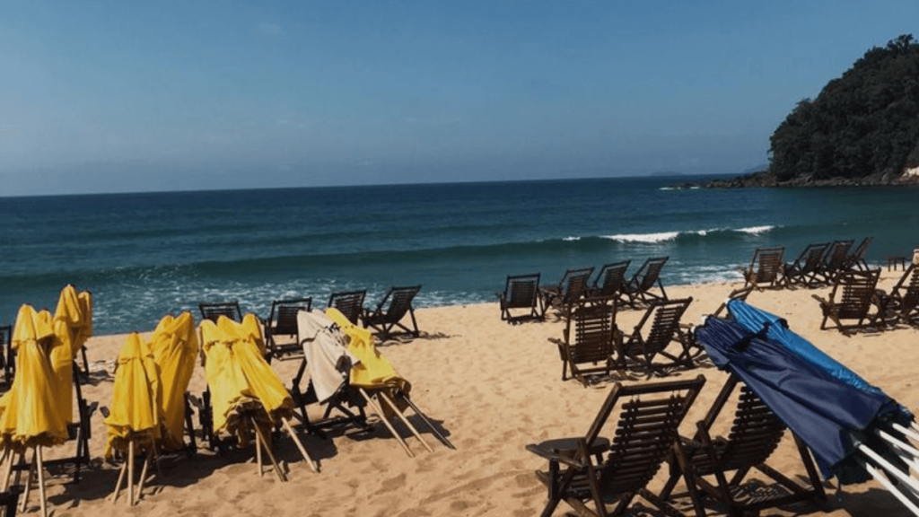 praia do prumirim em ubatuba, com cadeiras, guarda sois amarelos, mar azul