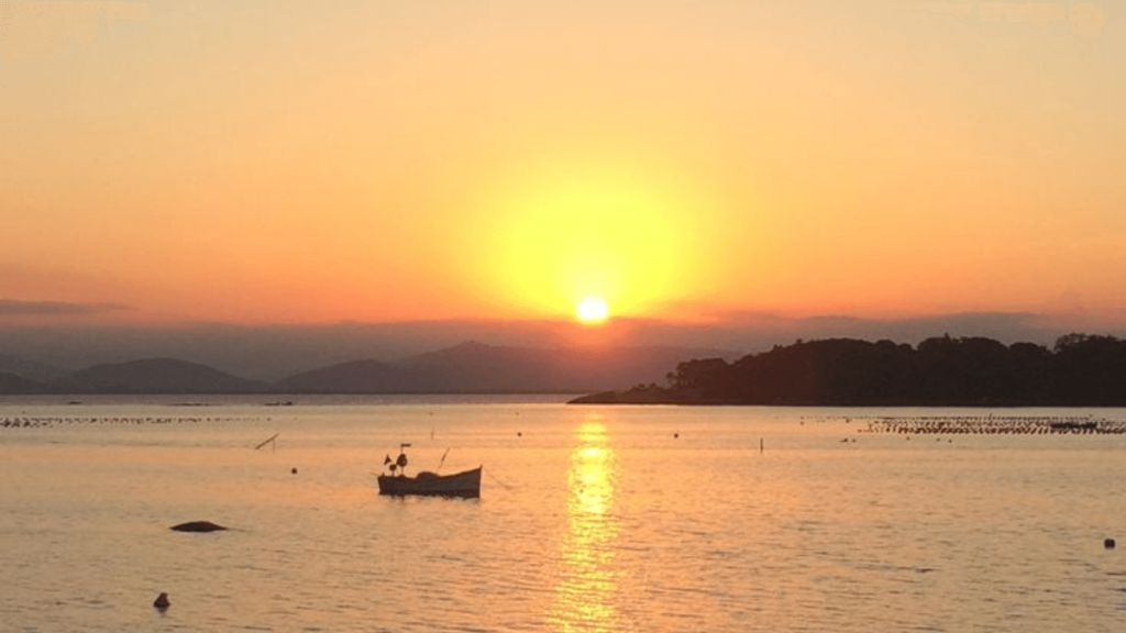 por do sol na praia com barcos no mar
