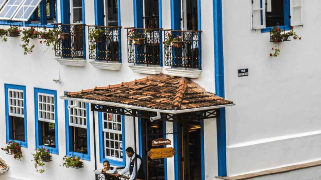 casa de ouro preto com vranda e plantas com dois homens, casa de cor branca com janelas azuis