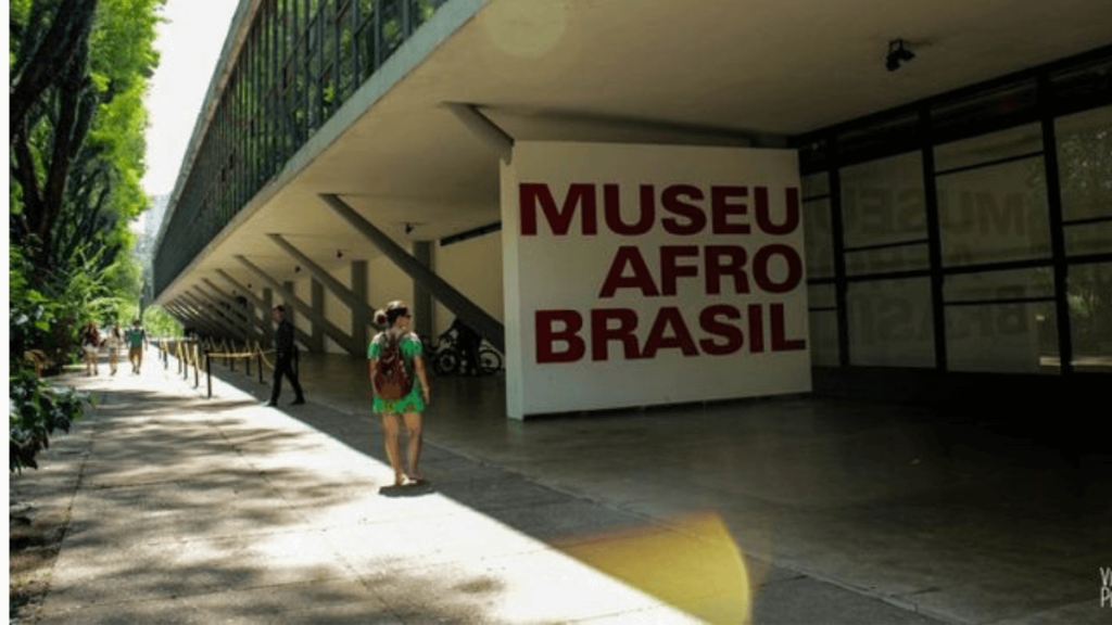 faxada do museu em letras grandes e vermelhas em um quadrado branco, "Museu Afro Brasileiro", alguns turistas ao redor