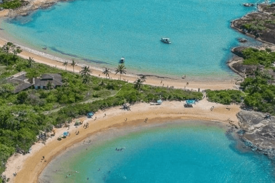 praia de guarapari com muita vegetação, areia branca e mar limpo