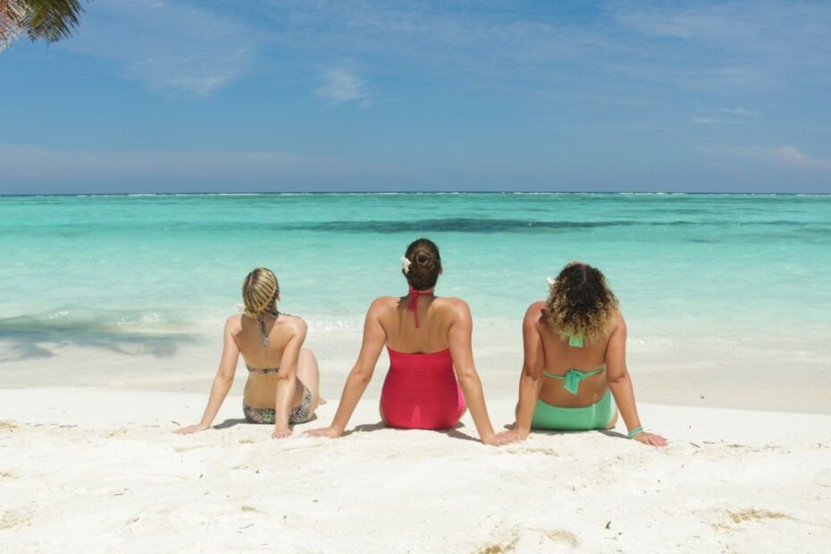 Melhores destinos de férias no Brasil: 3 mulheres sentadas na praia olhando a paisagem