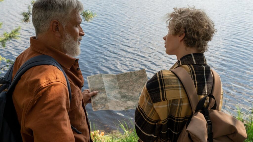 Casal olhando um mapa próximo de um lago.