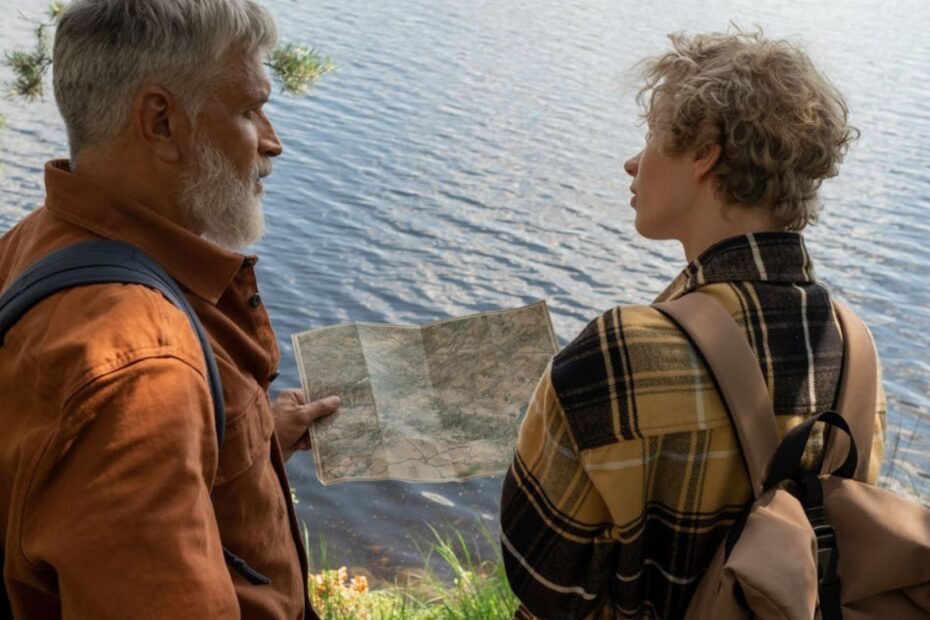 Casal olhando um mapa próximo de um lago.