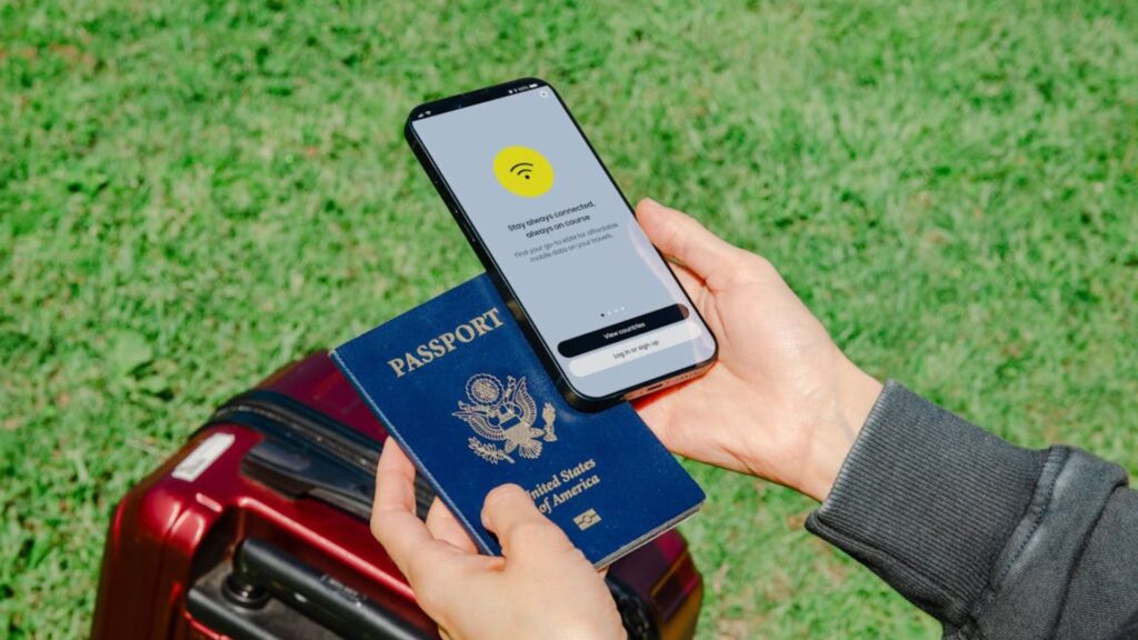 Pessoa segurando o Passaporte com o celular na outra mão.